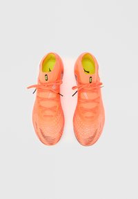 Kirkkaan oranssit urheilukengät, joissa on verkkomainen päällinen, teksturoidut yksityiskohdat, tasaiset nauhat ja keltainen pohjallinen. Sivussa näkyy brändäys.