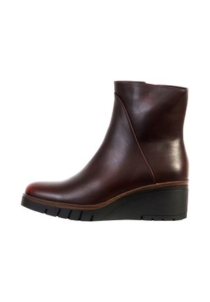 Bottine en cuir marron foncé avec talon compensé et semelle noire rainurée, vue de profil sur fond blanc.