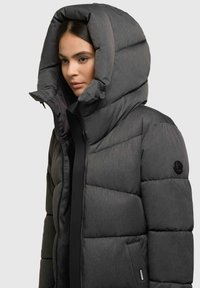 Giacca a vento in grigio scuro con cappuccio alto imbottito, chiusura a zip, tessuto texturizzato e dettaglio del logo sulla manica.