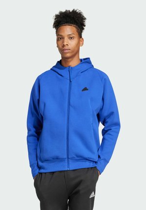 Sudadera azul con cremallera fabricada en un tejido suave y con capucha a juego. Presenta un pequeño logo negro en el pecho y puños acanalados.