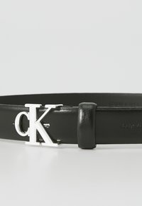 Fekete bőr öv ezüst színű "CK" logós csattal. Simább felülettel és elegáns dizájnnal rendelkezik, állítható hurkos tartóval.