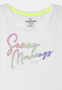 Camisa de manga curta branca com decote redondo. Apresenta texto multicolorido com a inscrição "Morangos Ensolarados", com um detalhe em verde-neon no decote.
