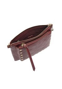 Burgundowa skórzana kopertówka z złotymi ćwiekami po jednej stronie, zamek błyskawiczny oraz odpinany pasek na nadgarstek. Wnętrze wyłożone jest pasującym materiałem.