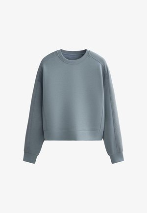 Skraťená mikina v mäkkej, tlmenej modrej látke. Má dlhé rukávy, okrúhly výstrih a rebrované akcenty pozdĺž ramien a manžiet.