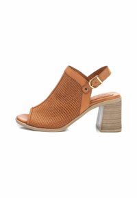 Sandal con tacco aperto in punta, di colore beige, con design superiore perforato, fascia alla caviglia e tacco a blocco spesso e texturizzato. Decorata con una fibbia dorata.