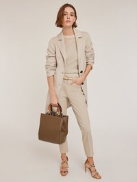 Beige maßgeschneiderter Blazer, gestreiftes Stricktop, helle Hose und braune Tasche mit Holzgriffen; Riemchenabsätze mit dekorativen Elementen.