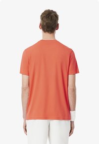 Kortärmad, rundhalsad sportskjorta i klar korallorange. Tillverkad av ett mjukt, lätt tyg med normal passform. Inga synliga logotyper.