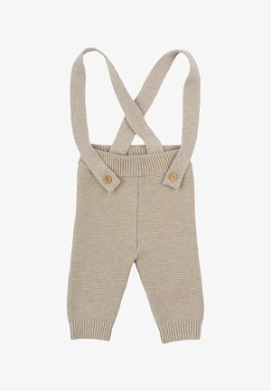 Salopette en tricot beige avec des bretelles croisées, deux boutons en bois sur le devant, jambes effilées et un motif texturé sur l'ensemble.