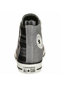 Černobílé vysoké tenisky s kostkovaným vzorem, gumovou podrážkou a nášivkou s hvězdou na vnější části kotníku. Viditelné vyztužené švy.