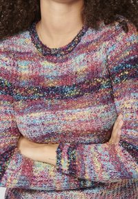 Pull en laine multicolore avec un col rond et des manches longues. La texture est duveteuse avec des rayures horizontales en violet, bleu et jaune.