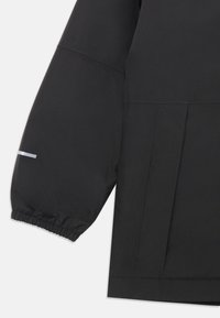 Schwarze wasserdichte Jacke mit elastischen Bündchen, lockerer Passform und einem reflektierenden Streifen auf dem Ärmel. Glatte Textur und minimalistisches Design.