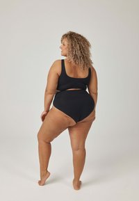 Czarny dwuczęściowy strój kąpielowy z krótkim topem na szerokich ramiączkach i wysokim stanem majtek. Gładka faktura, minimalistyczny design, widok od tyłu.