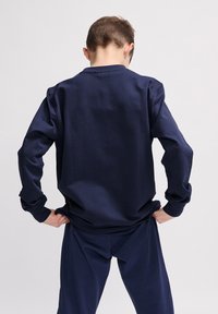 Felpa e pantaloni blu navy, realizzati in un tessuto liscio. La felpa ha maniche lunghe e un semplice scollo rotondo.