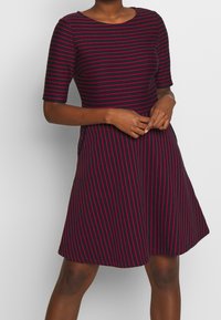 Navykleid mit kurzen Ärmeln, mit rosa horizontalen Streifen. A-Linien-Form, runder Ausschnitt, weicher Baumwollstoff und knielanger Saum.