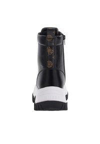 Bottines en cuir noir avec une semelle blanche, dotées d'une fermeture éclair, d'un passepoil à motif à l'arrière et d'un logo en relief sur le talon.