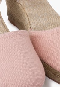 Espadrilles en toile rose avec une semelle intérieure en tissu beige texturé et une semelle plateforme en corde naturelle. Bout arrondi et détails cousus.
