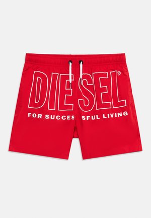 Czerwone spodenki kąpielowe z białymi troczkami i dużym białym napisem "DIESEL" na przodzie, częściowo pokazującym tekst "FOR SUCCESSFUL LIVING."