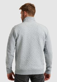 Grijze gewatteerde sweatshirt met een hoge kraag, lange mouwen en geribbelde manchetten. Zijdelingse zakdetails en textiel met structuur.