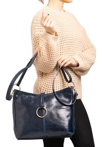 Borsa in pelle blu con una trama liscia, accentuata da un anello in tonalità oro, doppio manico per spalla e un design minimalista.