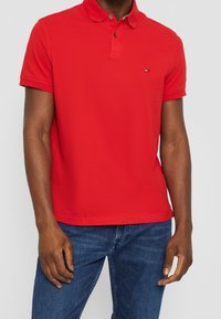 Polo shirt rouge en coton, avec un col classique, une patte de boutonnage, des manches courtes et un petit logo sur la poitrine gauche.