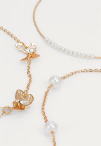 Gold-tone necklace featuring round pearls and a butterfly clasp with a rhinestone accent. Includes a beaded section with small pearls.