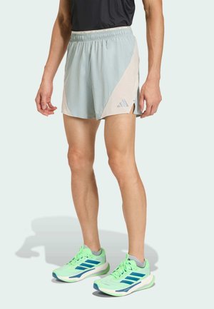 Light blue running shorts with a white accent, featuring an elastic waistband and logo. Paired with neon green running shoes with blue stripes.