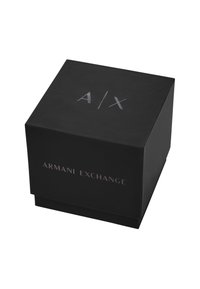 Melnas kvadrātveida iepakojums ar gludu matētu virsmu. Satur reliģētas sudraba burtus "A/X" un "ARMANI EXCHANGE" uz dažādām malām.