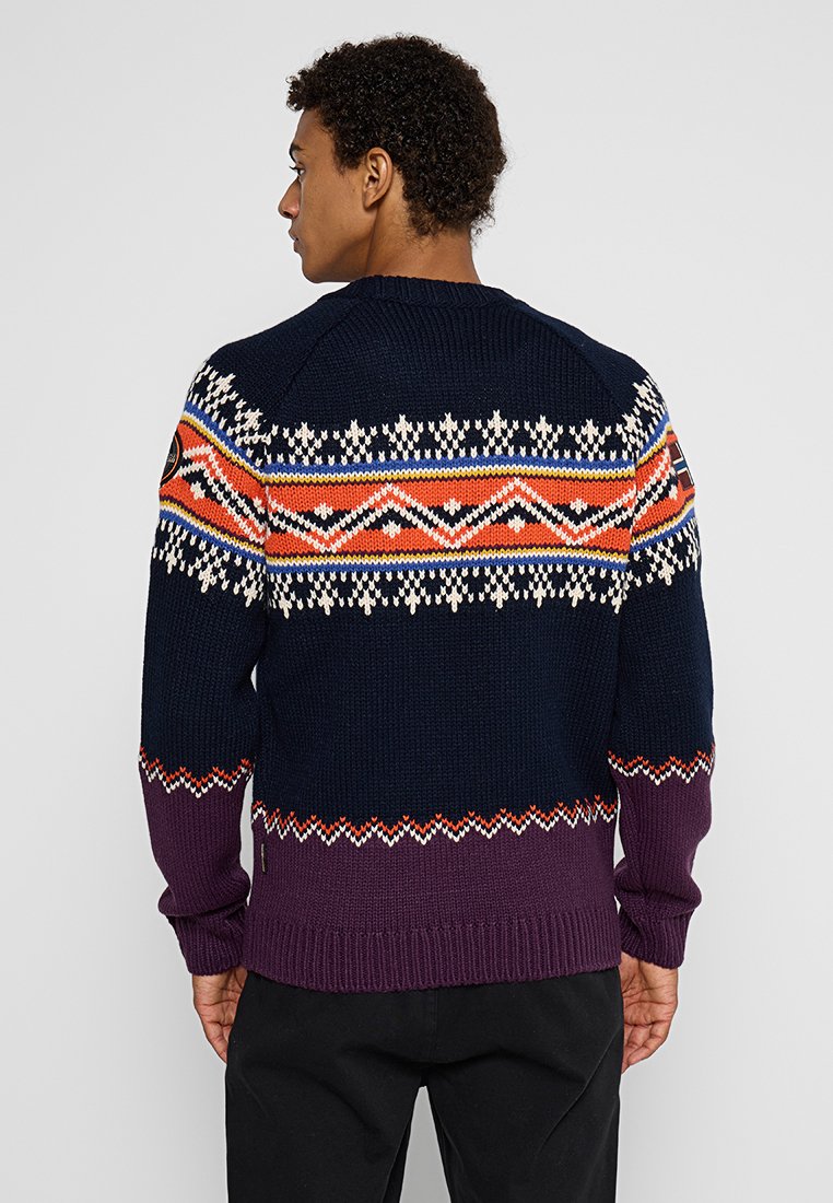 Pull en tricot marine avec des motifs géométriques multicolores sur les épaules, se dégradant vers un ourlet côtelé et des poignets violet profond.