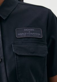 Black work shirt featuring a button-down collar, two chest pockets, and a woven label with "Dickies x Harley-Davidson" branding.