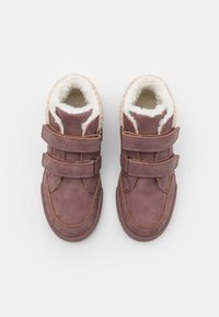 Chaussures hautes en simili cuir marron avec double bande Velcro, doublure en fausse fourrure crème et coutures contrastantes. Design à bout rond.