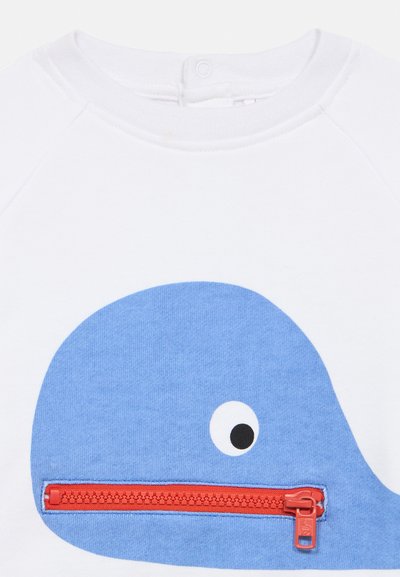 Witte sweatshirt met een blauwe walvisafbeelding met een zwart oog en een rood ritssluitingaccent over de mond van de walvis.