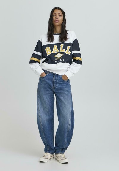Hanorac alb și bleumarin cu textul "BALL", asociat cu blugi lărgi de culoare albastră. Ținuta este accesorizată cu dungi galbene și teniși albi casual.