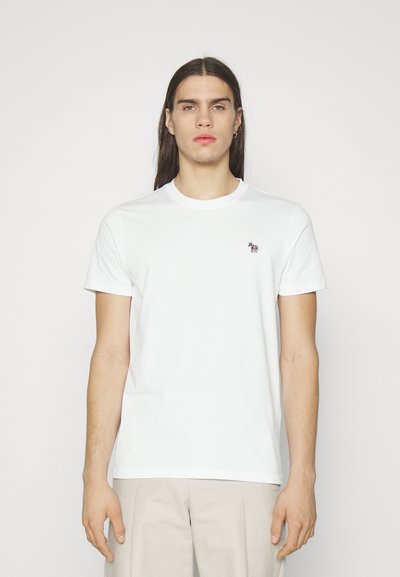 T-shirt en coton blanc avec un col rond et des manches courtes. Présente un petit motif brodé sur la poitrine gauche. Texture lisse.