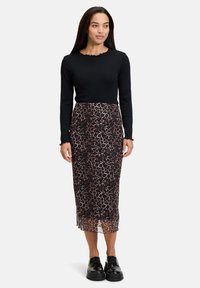 Zwarte langärmelige top met een geschulpte halslijn, gecombineerd met een midi-jurk met luipaardprint. De outfit heeft een doorzichtige, gestructureerde overlay en dikke zwarte schoenen.