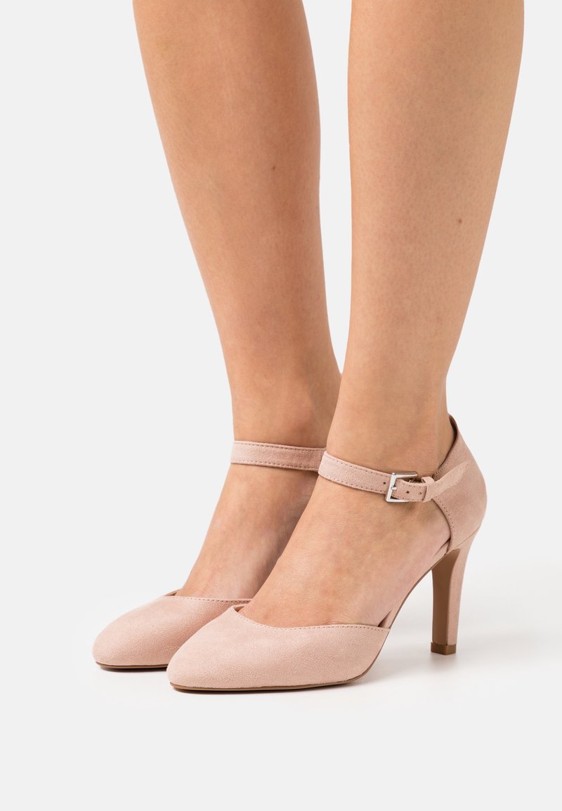 Chaussures à talons hauts en daim rose avec bout pointu et bride de cheville ornée d'une boucle argentée. Texture lisse et design épuré qui renforcent l'élégance.