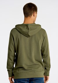 Sudadera de color verde oliva con capucha ajustable, mangas largas y puños acanalados. Textura suave y corte holgado, adecuada para un uso casual.