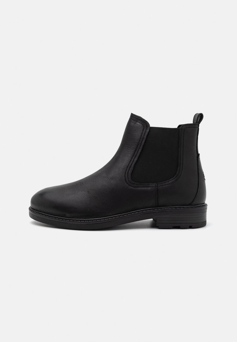Botas de cuero negro hasta el tobillo con paneles laterales elásticos, punta redondeada y tacón bajo. Presentan costuras visibles a lo largo de la suela y una asa en la parte posterior.