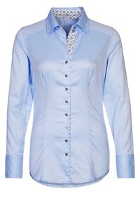 Ljust blå skjorta med lång ärm, med ett mönstrat kragefoder. Svarta knappar längs fram. Slät tygtextur.