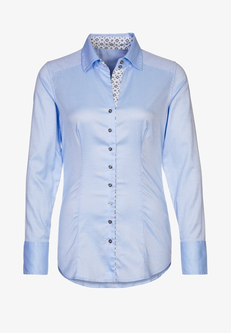 Ljust blå skjorta med lång ärm, med ett mönstrat kragefoder. Svarta knappar längs fram. Slät tygtextur.