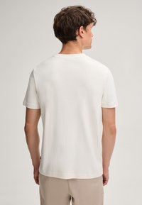 Witte katoenen t-shirt met korte mouwen, een ronde halslijn en een iets gestructureerd oppervlak. De achterkant is glad zonder zichtbare patronen of accenten.