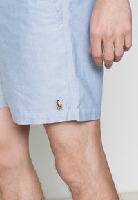 Ljusblå bomullsshorts med avslappnad passform. Detaljer med sömmar och en liten broderad logotyp av en ryttare på vänster lår.
