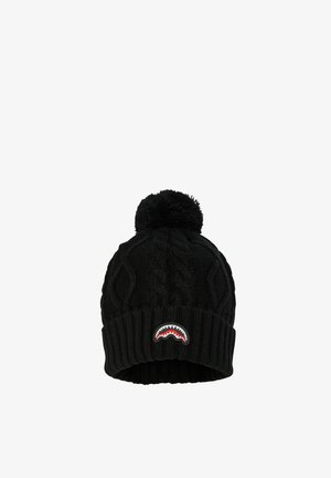 Gorro de punto negro con un patrón texturizado de cables, que cuenta con un pompón en la parte superior y un parche de dientes de tiburón en rojo y blanco en el frente.