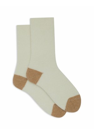 Calze color crema con una texture morbida, caratterizzate da punta e tallone marroni. Progettate con un bordo a coste per una vestibilità sicura.