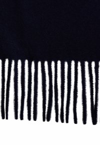 Bufanda de lana marinera con acabado texturizado, que presenta largos bordes con flecos en hebras alternas de negro y blanco. Apariencia suave y cálida.