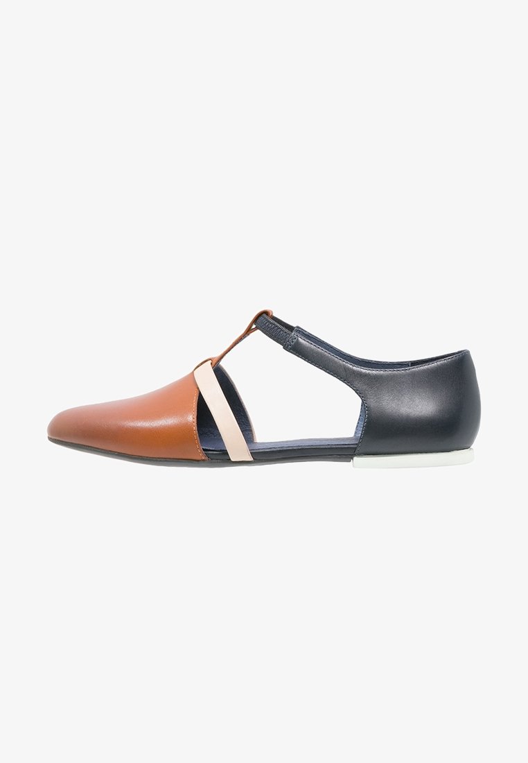 Chaussure femme plate avec bout pointu en cuir marron, talon noir, bride beige et fermeture élastique en T sur fond blanc.