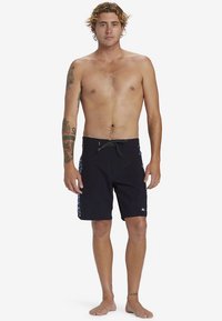 Czarne szorty kąpielowe z regulowanym paskiem ze sznurkiem i wzorzystymi wstawkami po bokach. Wykonane z lekkiego materiału, przeznaczone do aktywności wodnych.
