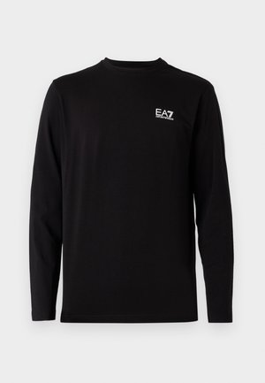 Svart långärmad skjorta i mjukt tyg. Har en liten vit logotyp på vänster bröstområde. Enkel, rund halsringning och rak passform.