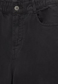 Svarta tygbyxor med en texturerad yta, elastiskt midjeband och knappstängning. Utöver det har de en sidoficka och detaljer med kontrasterande sömmar.