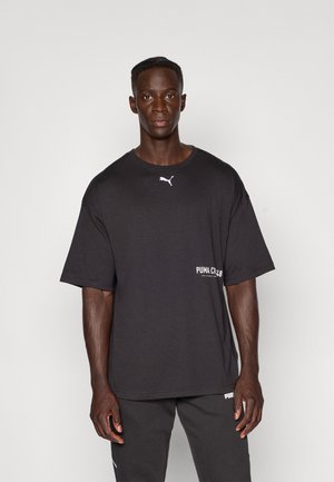 Zwarte oversized t-shirt van katoen, met een wit Puma-logo op de borst en een kleinere mernaam op de zijkant. Korte mouwen.
