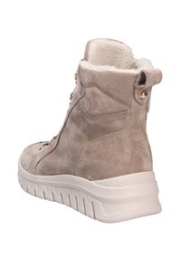 Bottines en suède beige avec un intérieur duveteux, des accents en métal doré et une semelle en caoutchouc blanc présentant un motif de semelle texturé.